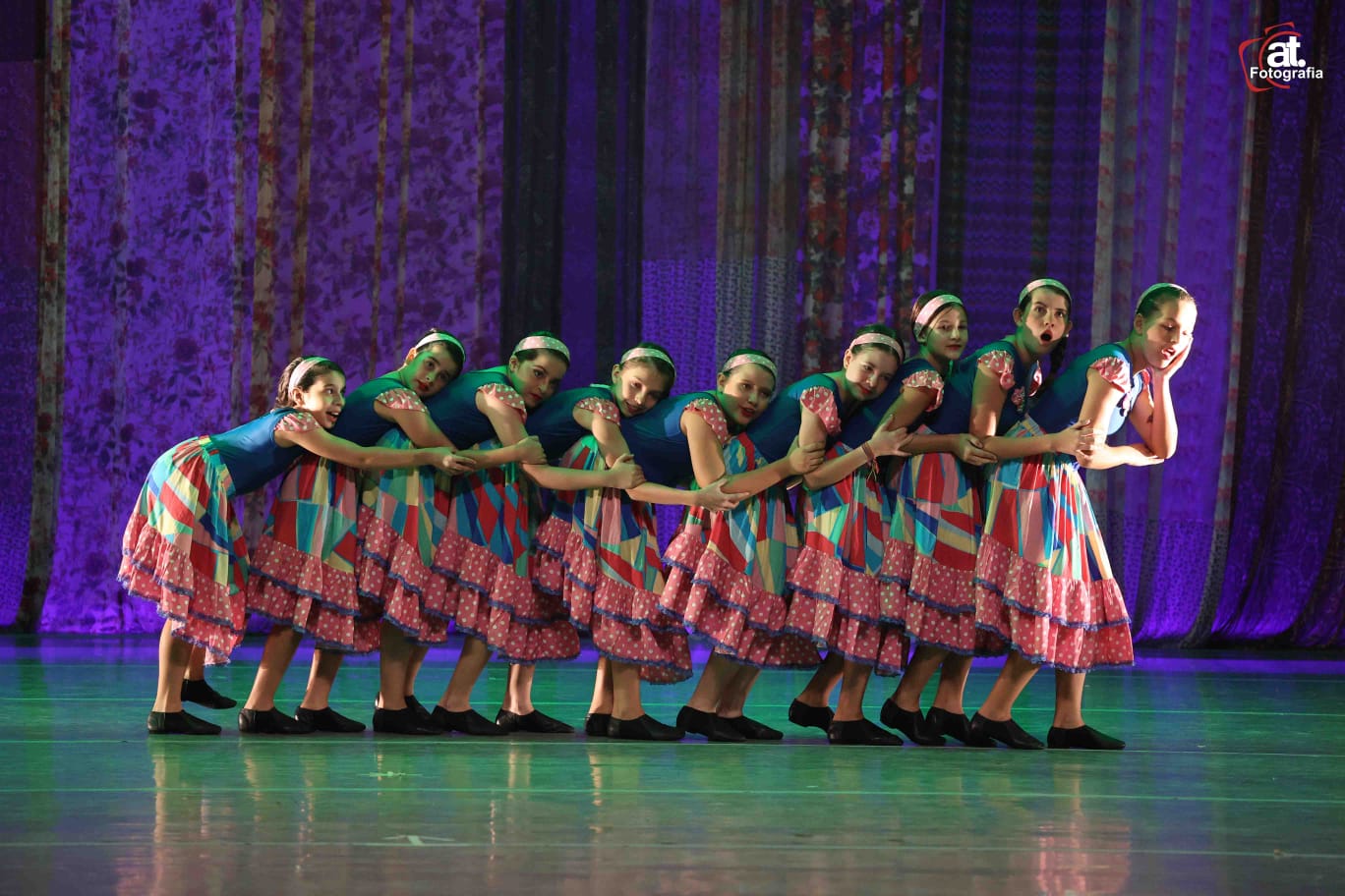 Fileira de alunas em coreografia com vestidos juninos